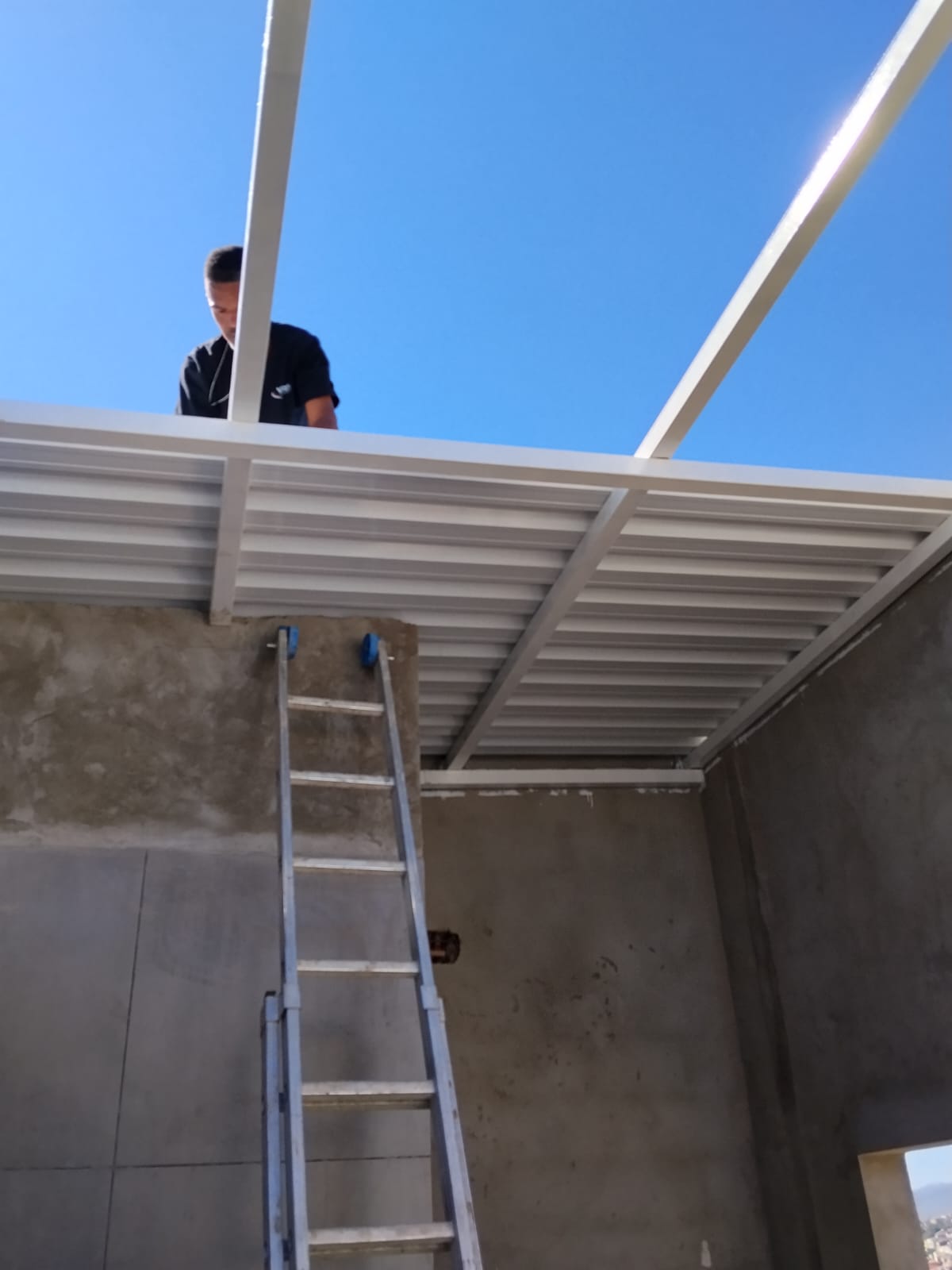 Instalador finalizando a montagem da cobertura metálica sobre laje
