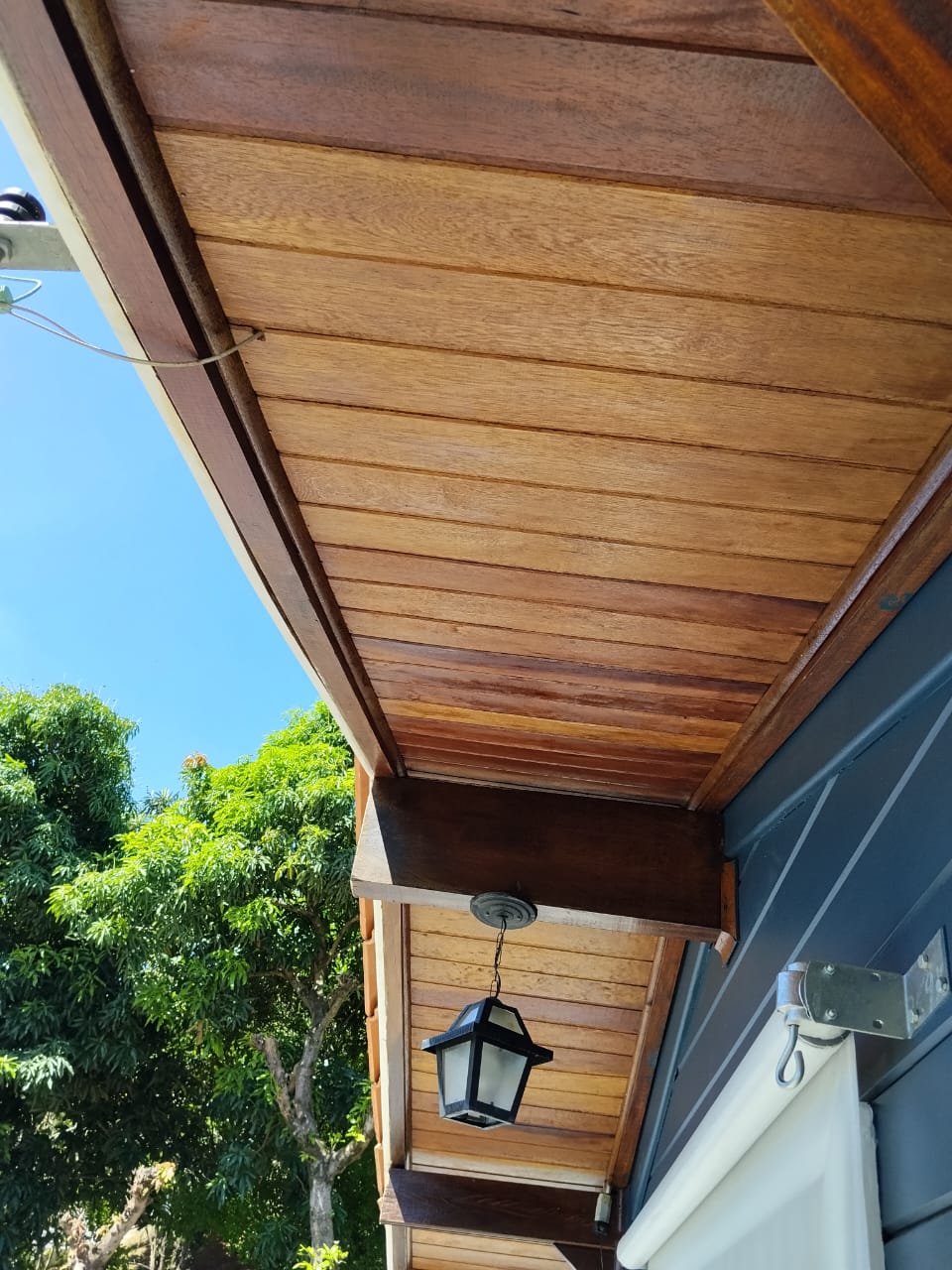 Forro de madeira com acabamento em verniz claro em fachada residencial