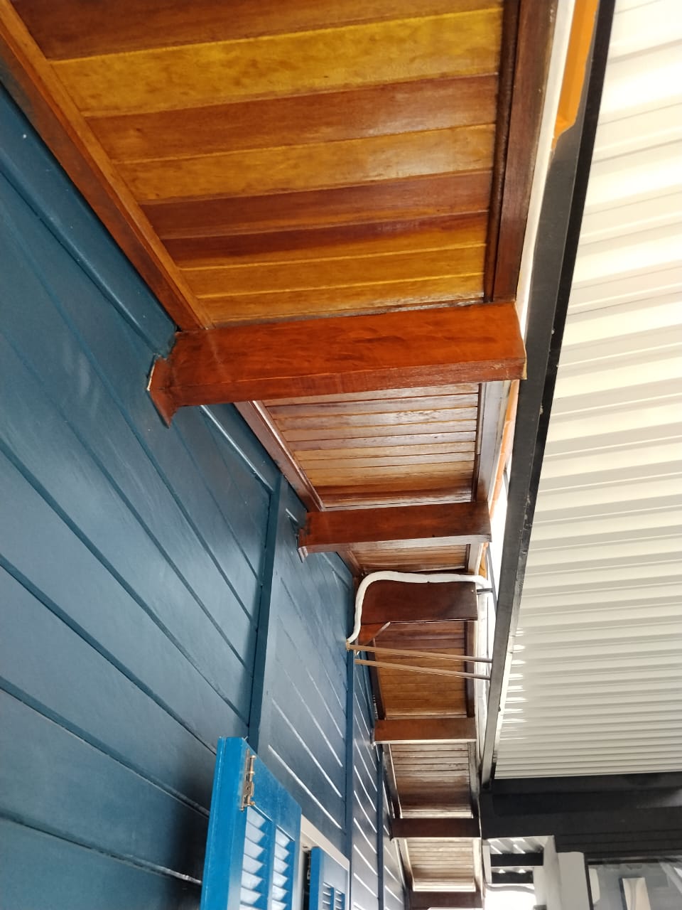 Forro de madeira envernizado em varanda com parede azul