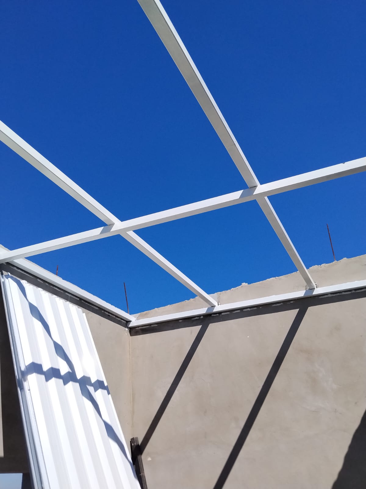 Detalhe da estrutura metálica pintada com céu azul ao fundo