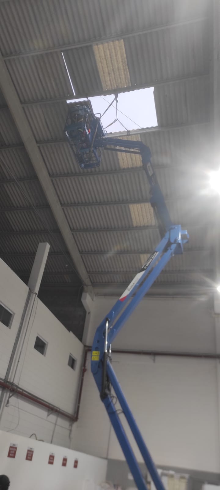 Equipe substituindo telhas metálicas em galpão industrial