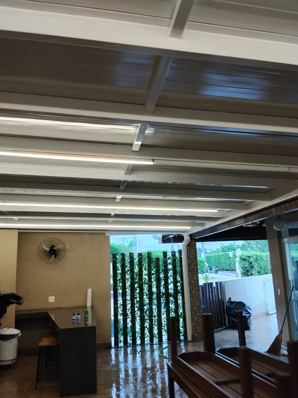 Área gourmet coberta com estrutura metálica branca e iluminação LED